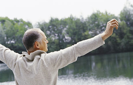 psychische Gesundheit Mann am See, streckt die Arme