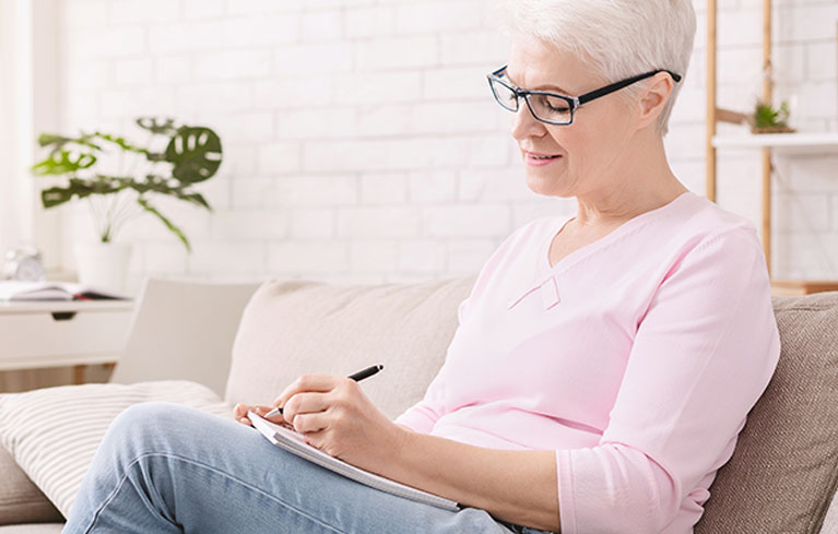 Allgemeines zu Krebs ältere Frau sitzt zu Hause und notiert sich etwas